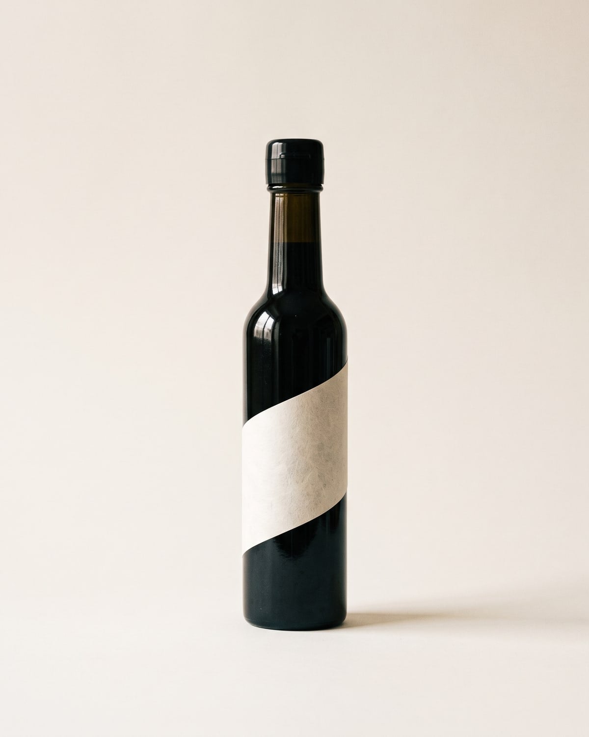 A slim light-blocking soy sauce bottle with a washi label set on the diagonal
