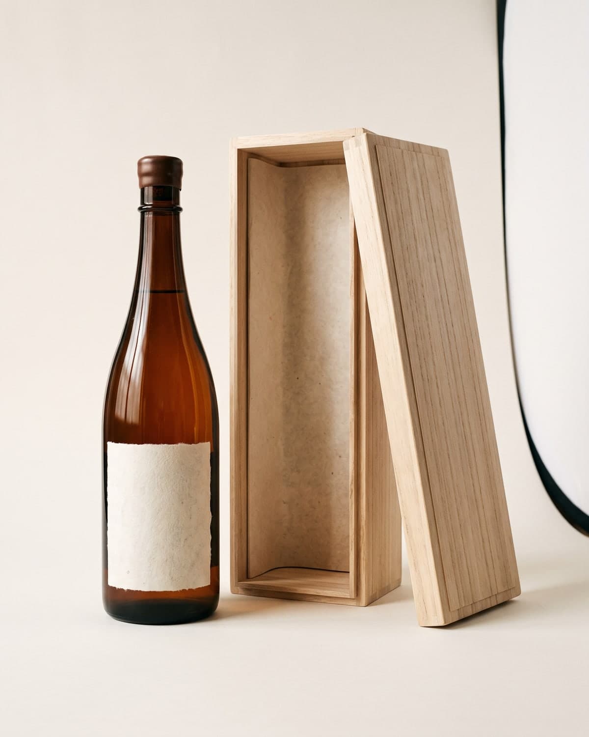 A dark bottle of amber aged sake beside its paulownia-wood box